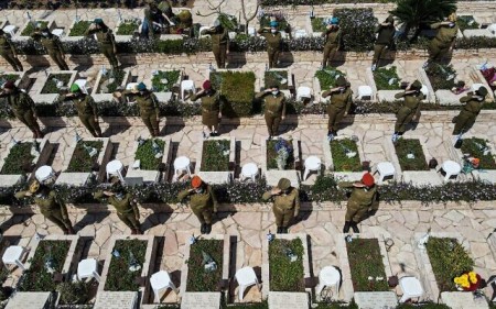 This picture taken on April 13, 2021, on Yom HaZikaron (Israel's Memorial Day) shows an aerial view of female Israeli soldiers performing salutes by graves at the Kiryat Shaul military cemetery in the Mediterranean coastal city of Tel Aviv. (JACK GUEZ / AFP)